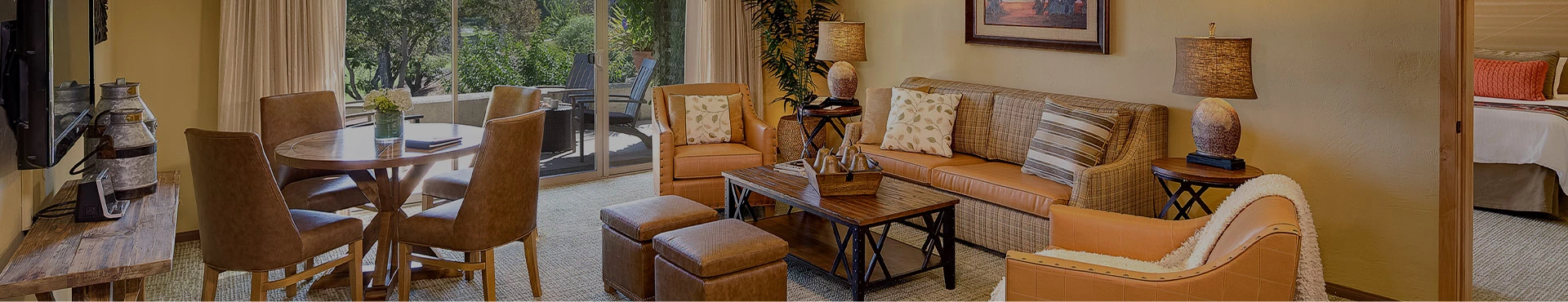 interior of a hotel guest room with a living room area complete with table and chairs, couch, and a balcony