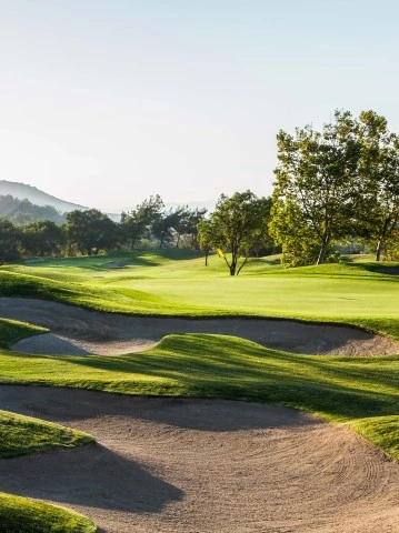 a golf course with sand bunkers and trees