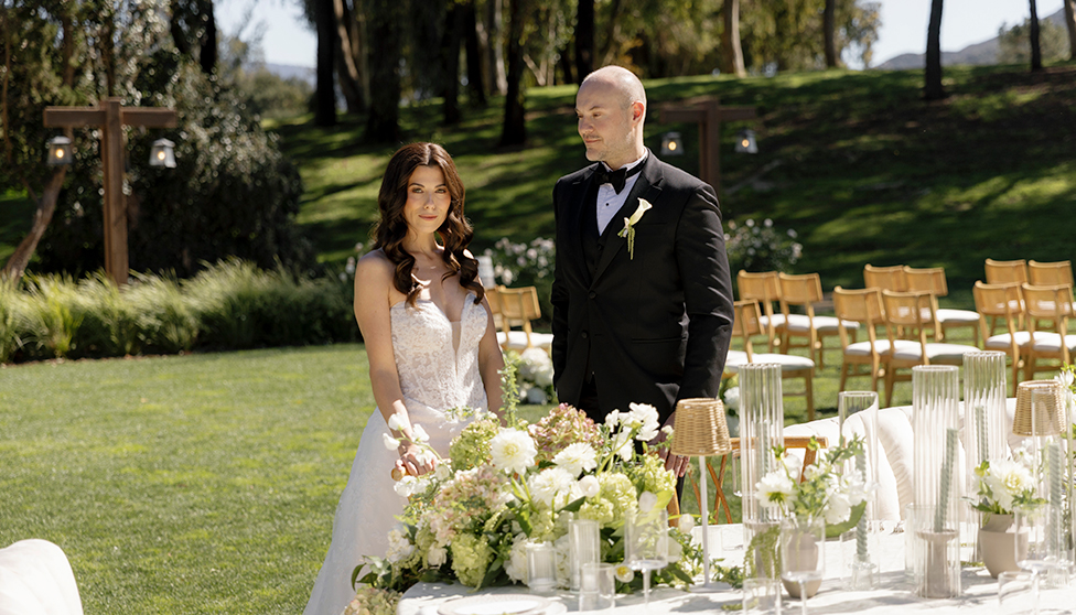 a man and woman standing next to a table with flowers