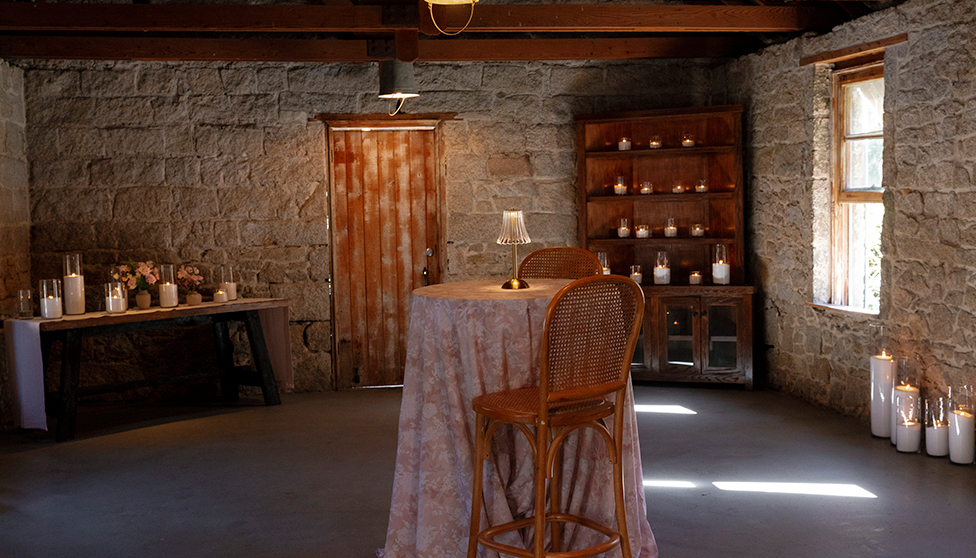 a table with a tablecloth and chairs in a room with a stone wall