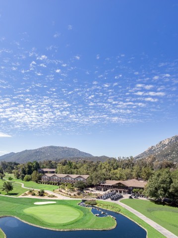 a golf course with a pond and a building in the background