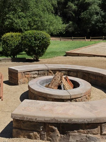 a fire pit with benches and trees in the background