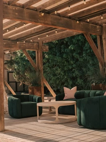 a patio with a wooden structure and green couches