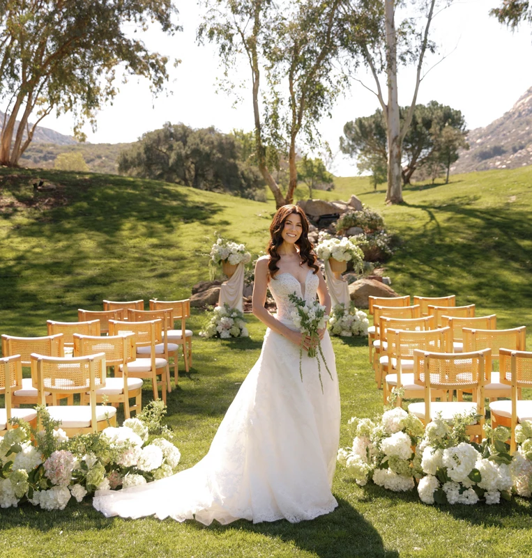 a woman in a wedding dress standing in a field of chairs