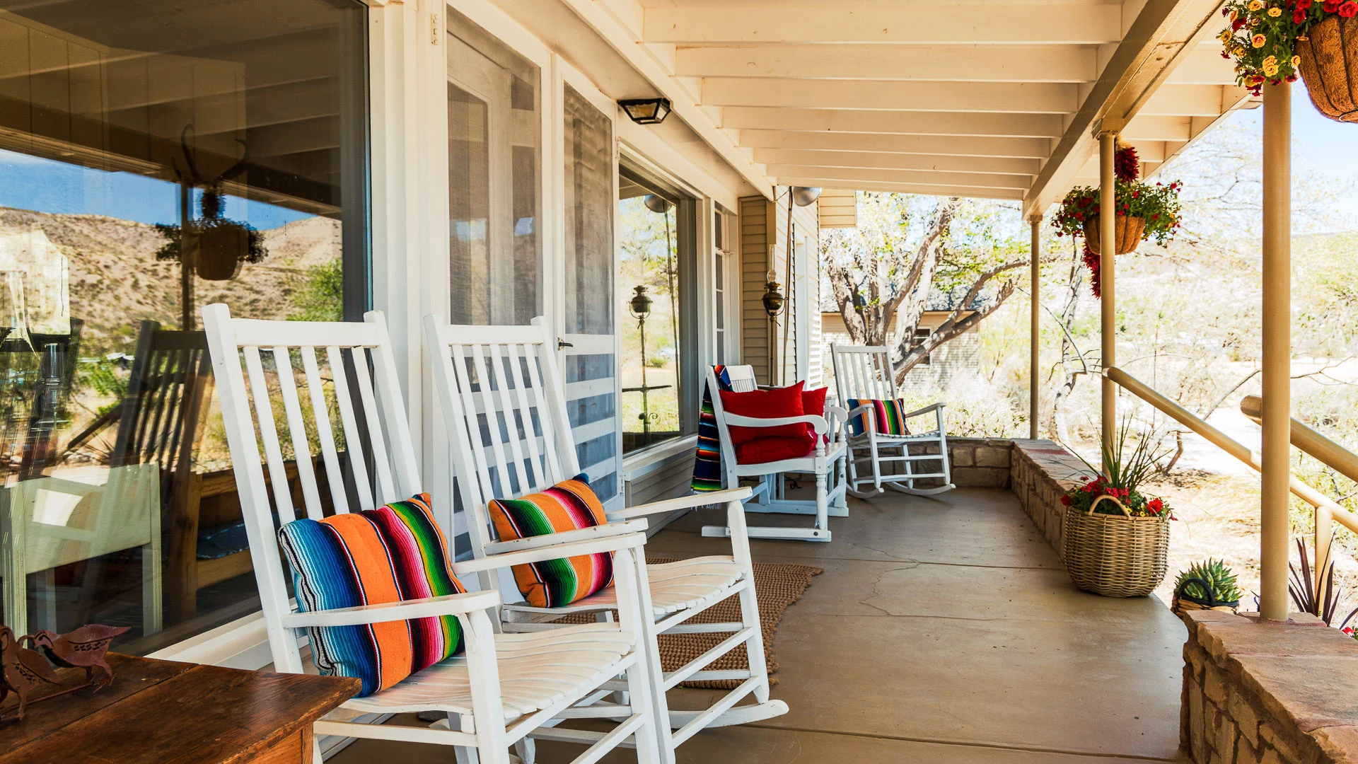 a row of white rocking chairs on a porch