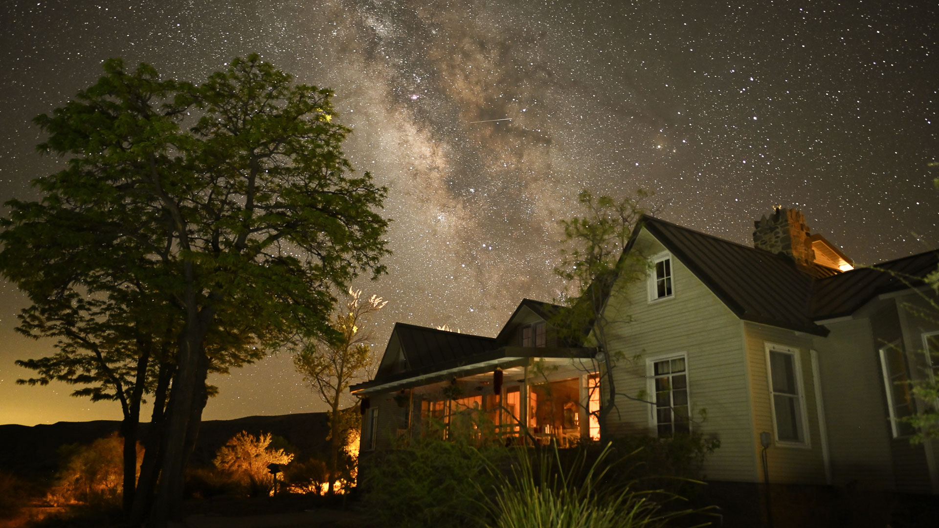 a house with a lit porch and trees in front of it
