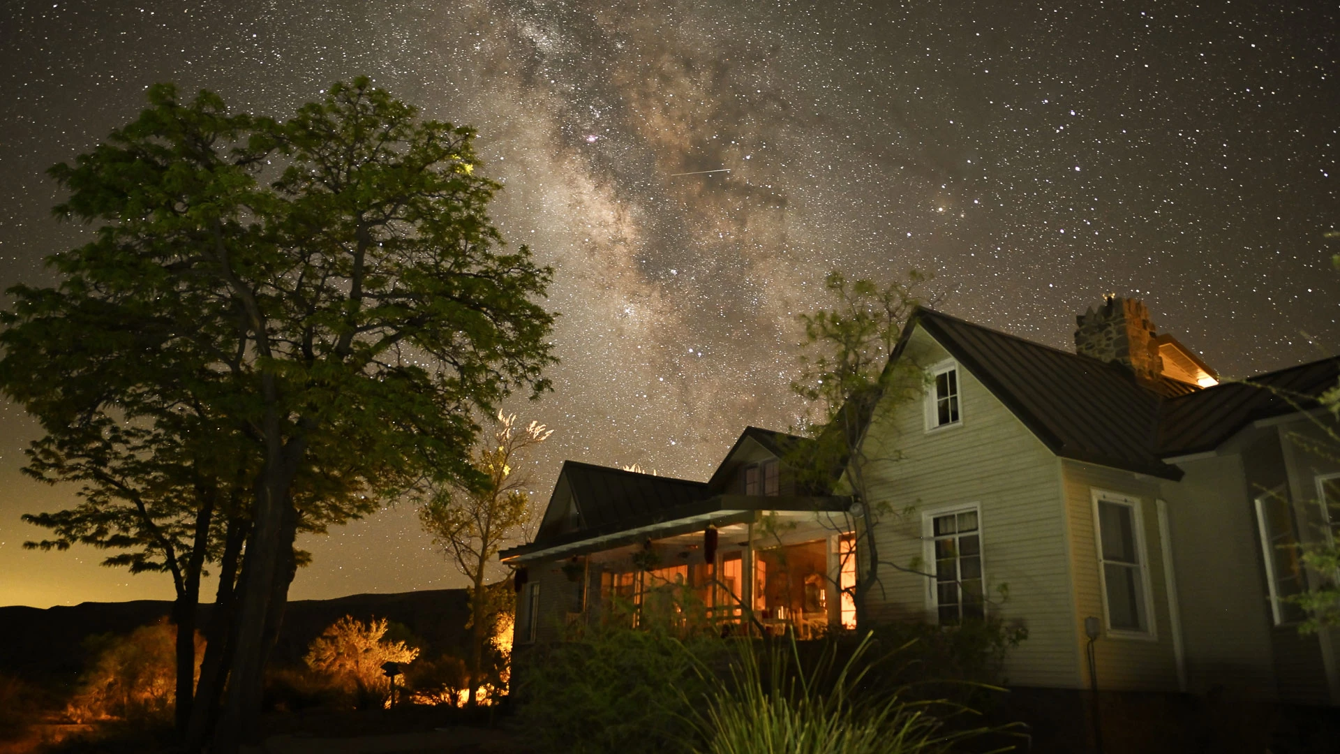 a house with a lit porch and trees in front of it