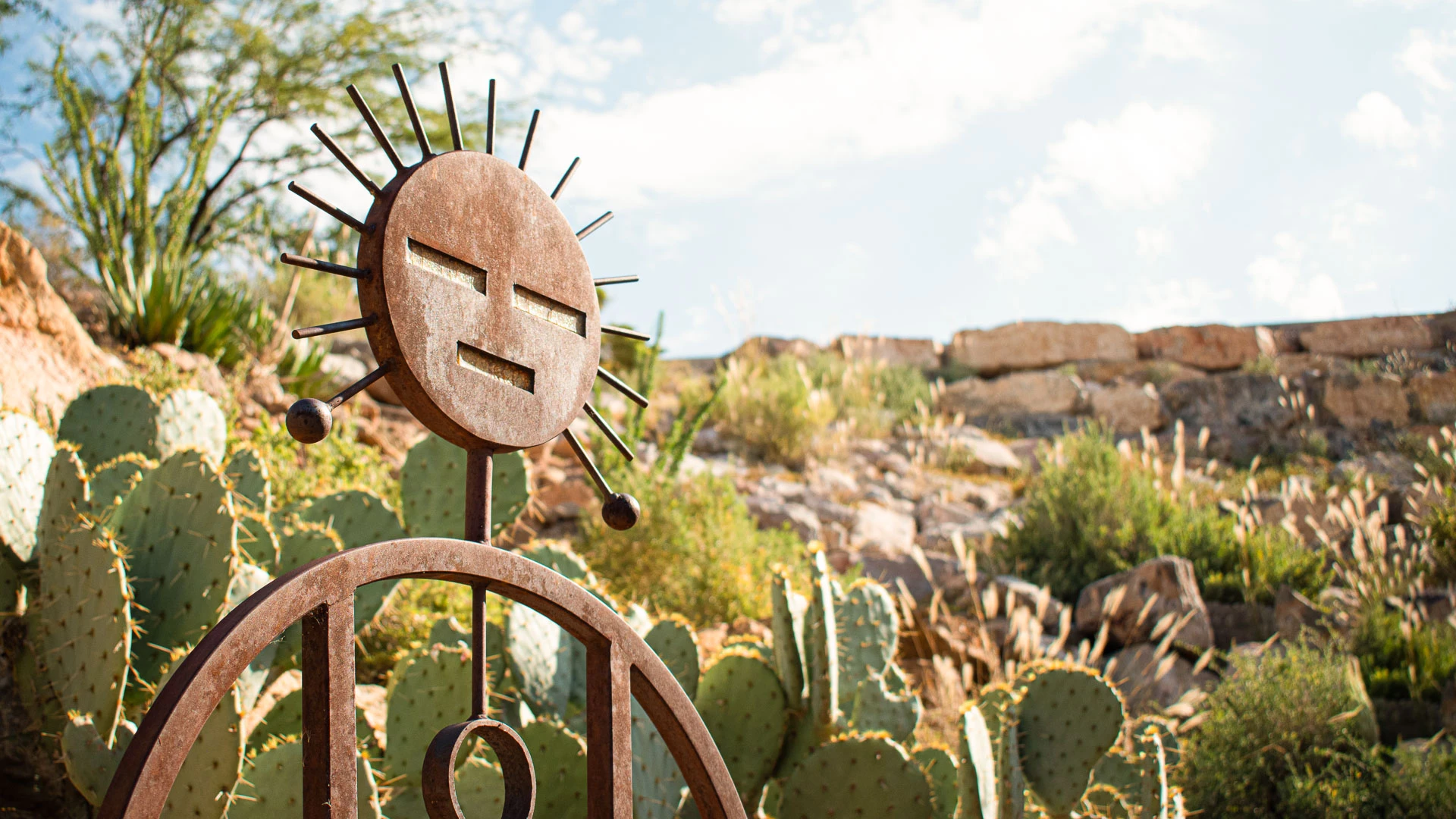 a metal sculpture in front of cactuses