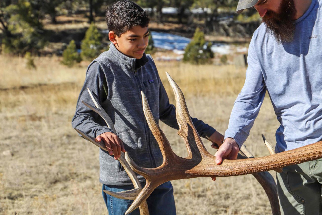 a man and boy holding antlers in a field