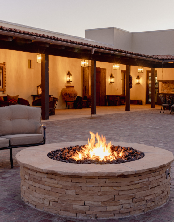 a fire pit with a couch and chairs in front of a home