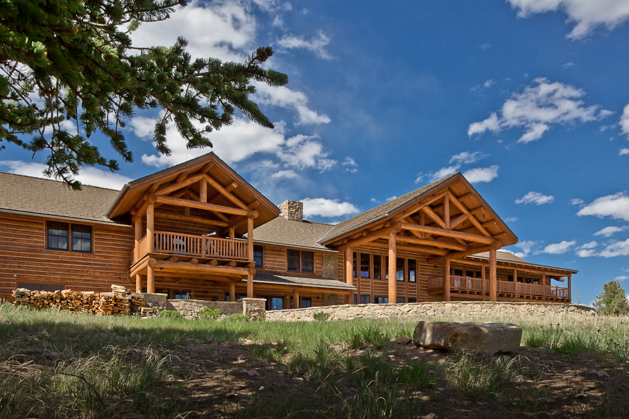 a large log cabin with a stone wall and a stone wall