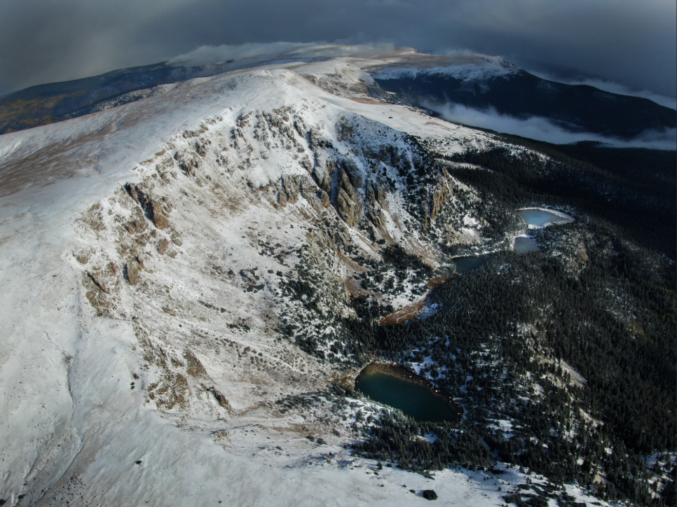 a snowy mountain with a lake and trees