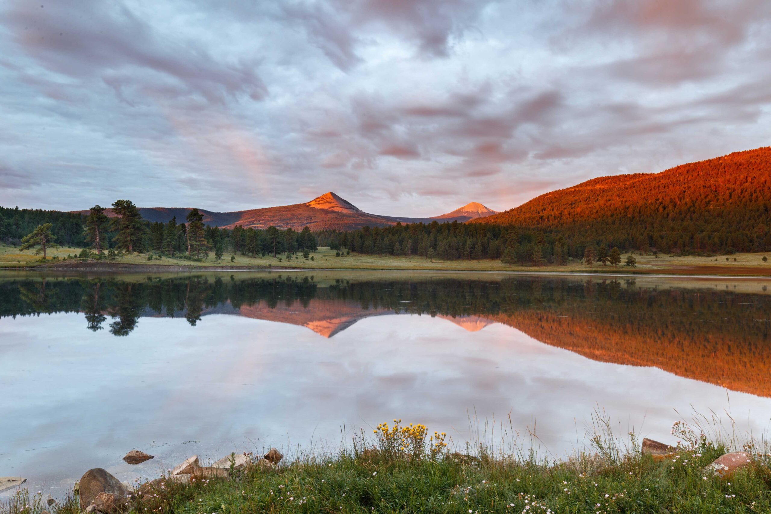 a lake with trees and mountains in the background