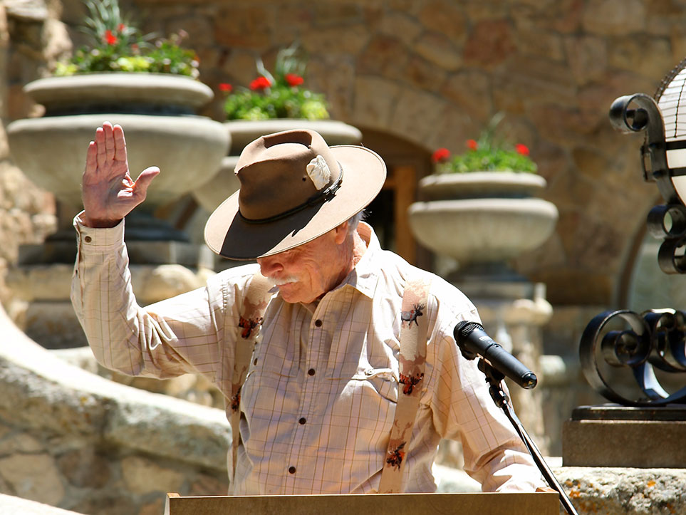 a man in a hat waving at a microphone