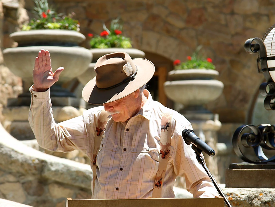 a man in a hat waving at a microphone