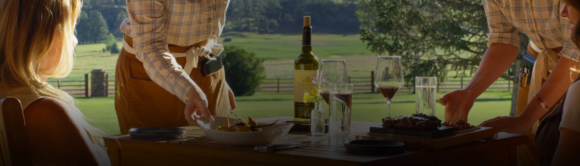 a man standing next to a table with a bowl of food and wine