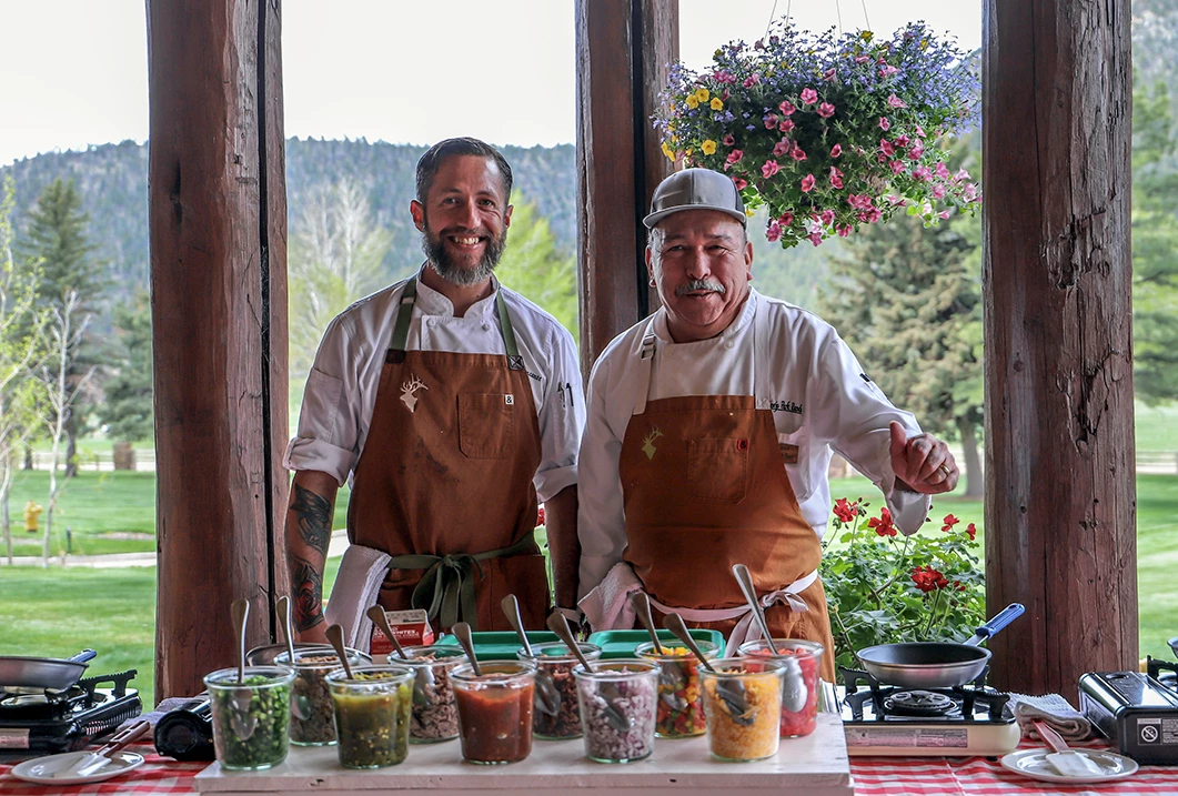 two men standing in front of a table full of food