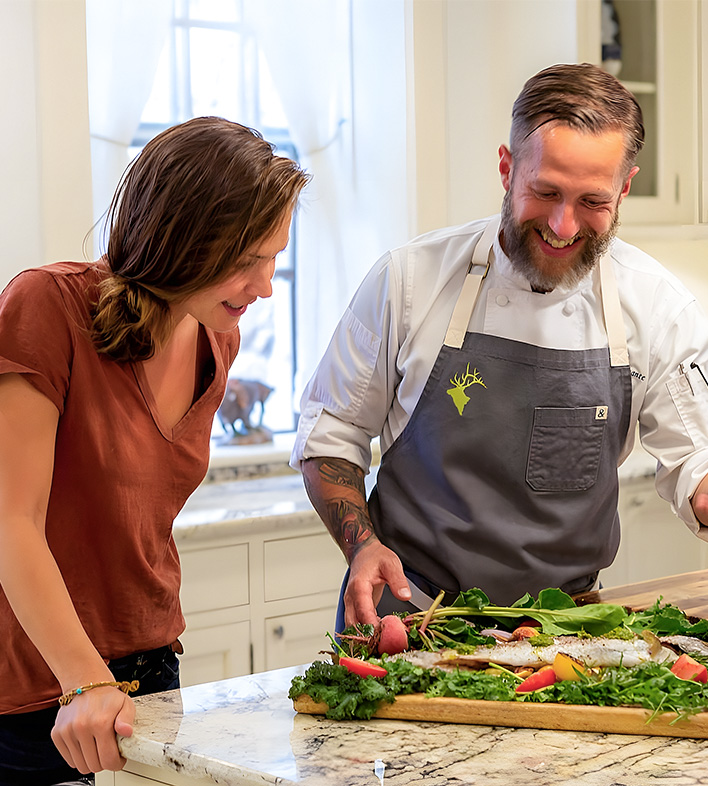 a man and woman standing in front of a table with food
