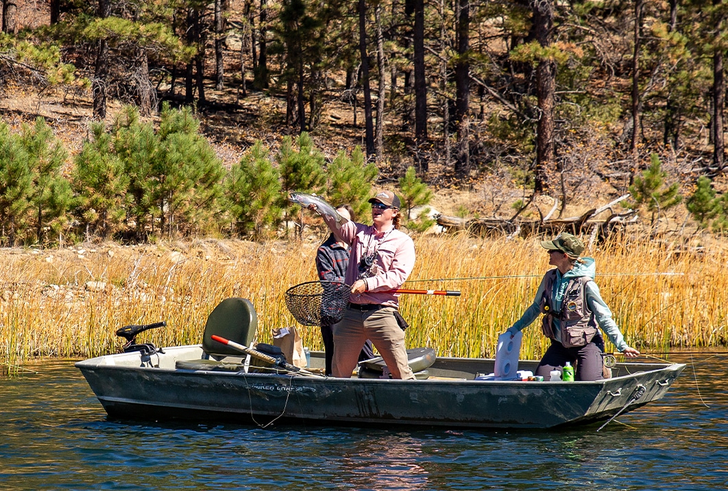 a group of people in a boat holding a fish