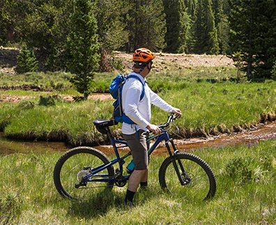 a man with a backpack on a bicycle in a grassy area