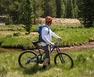 a man with a backpack on a bicycle in a grassy area