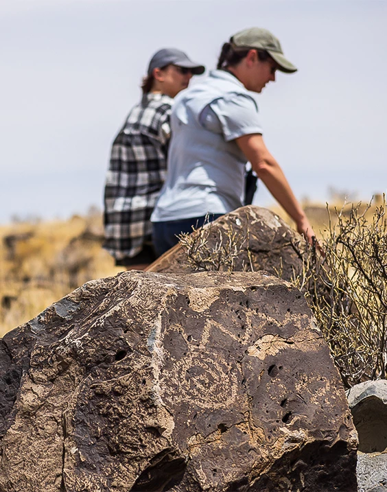 people looking at a rock with a drawing on it