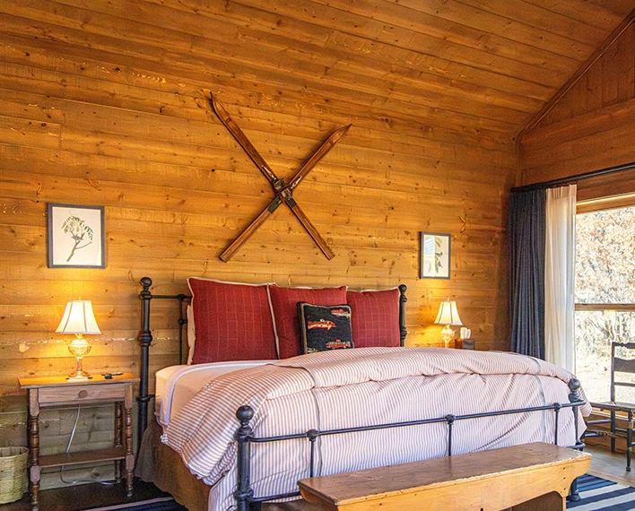a bed with pillows and a table in a log cabin