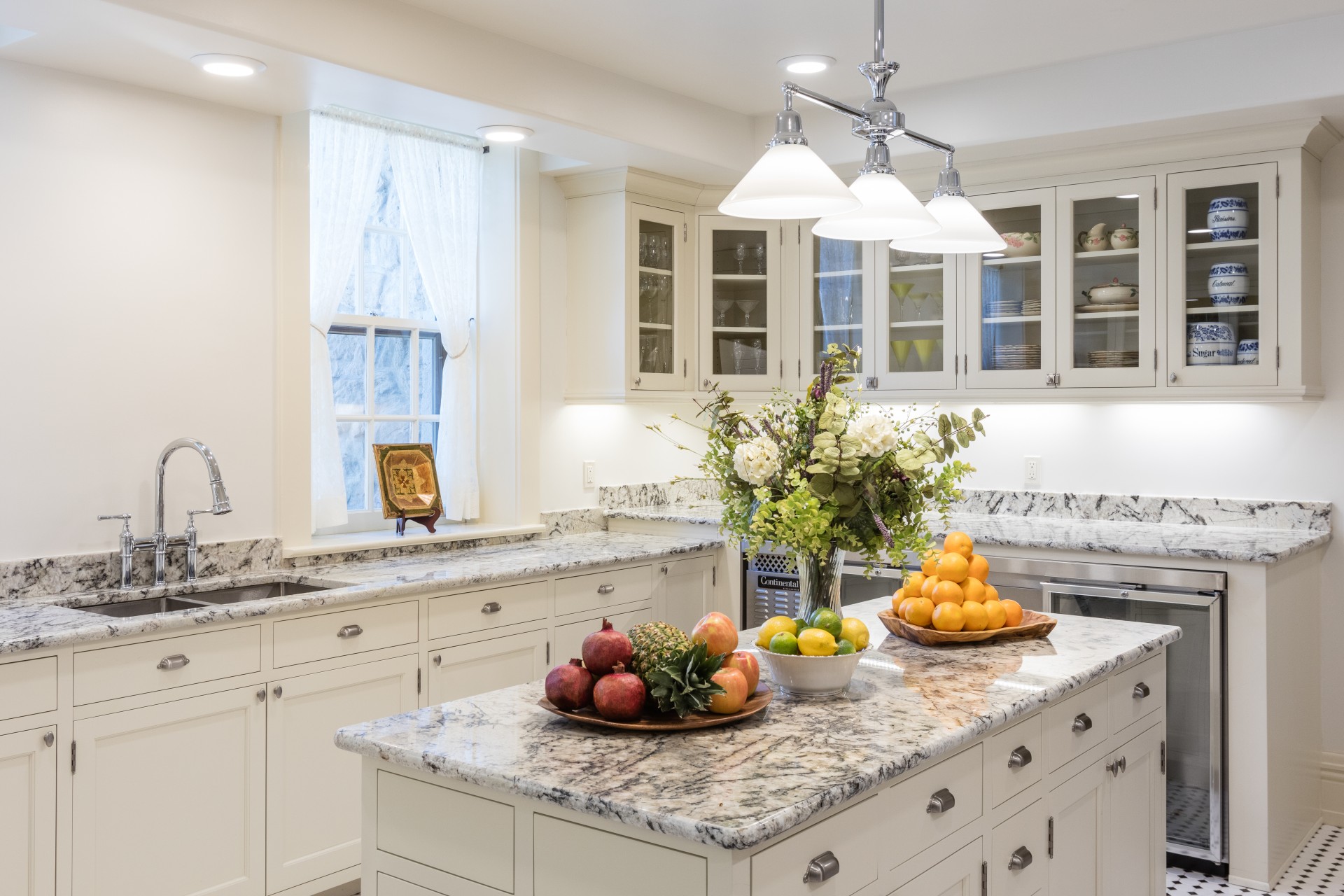 a kitchen with white cabinets and marble counter tops