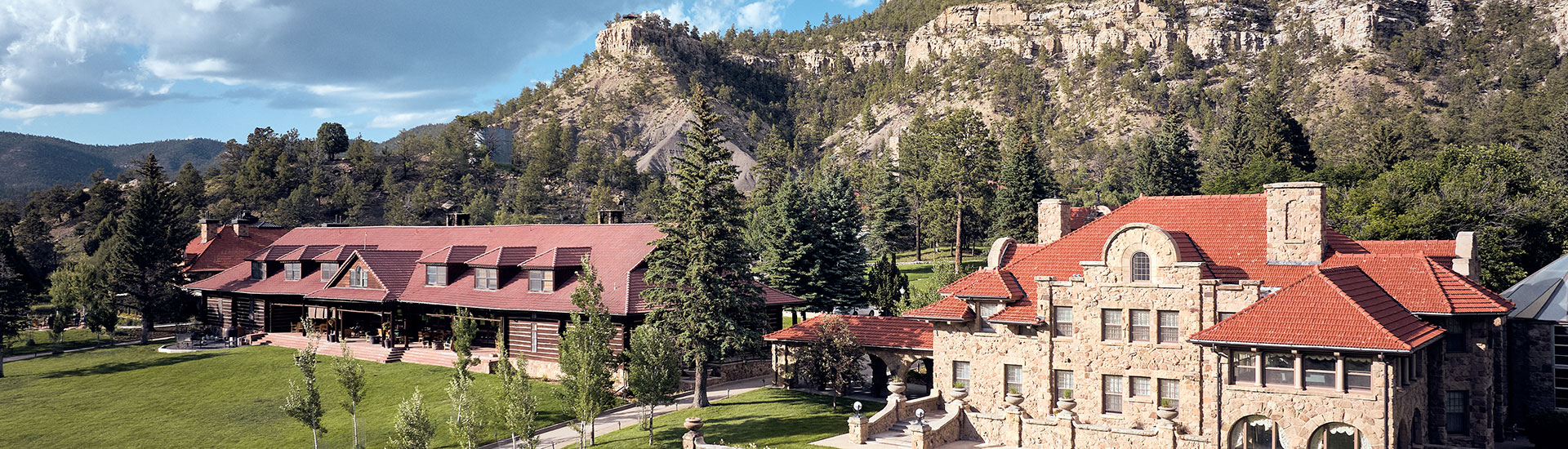 a group of houses with trees and mountains in the background