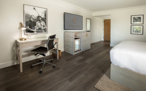 a room with a bed and a desk and a television