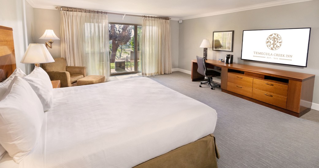 a room with a bed and a desk and a television