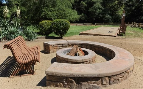 a fire pit with benches and trees in the background