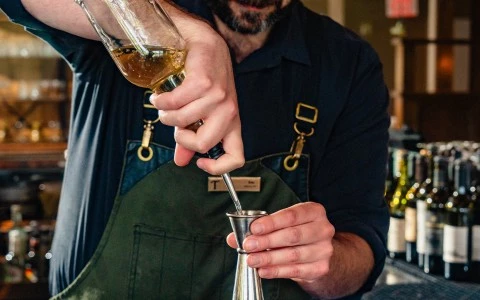 a man pouring liquid into a metal cup