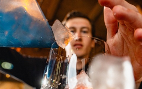 a person pouring ice into a glass
