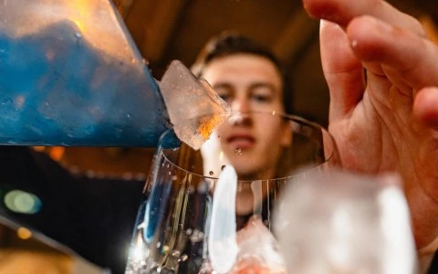 a person pouring ice into a glass