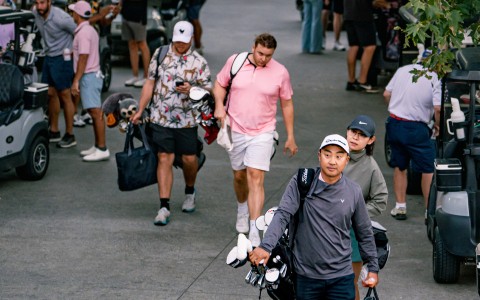 a group of people walking with golf clubs