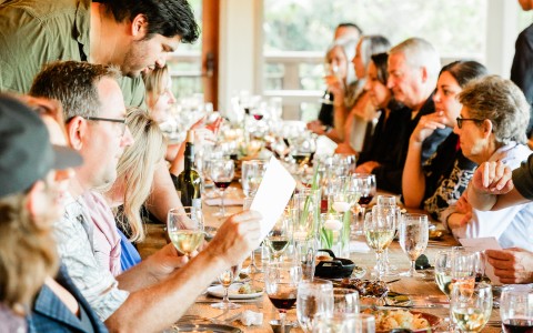a group of people sitting at a table with wine glasses and food
