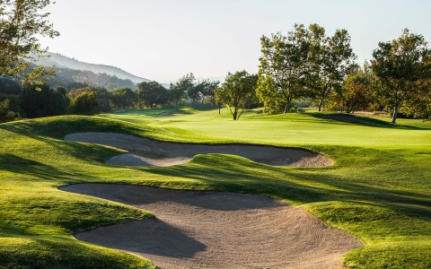 a golf course with sand bunkers and trees