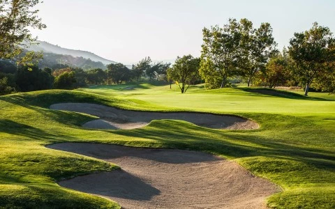 a golf course with sand bunkers and trees