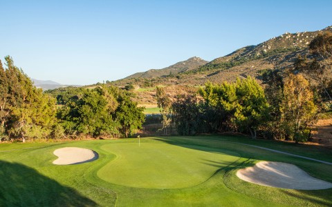 a golf course with sand bunkers and trees