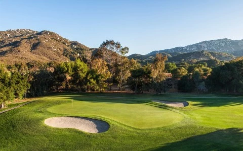 a golf course with sand bunkers and trees
