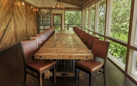 a large wooden table with brown chairs in a room with windows