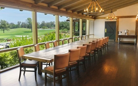 a long table with chairs in a room with a golf course view