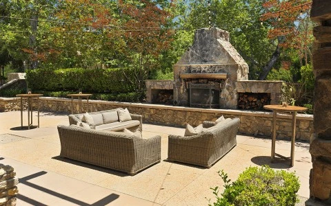 a patio with a stone fireplace and furniture