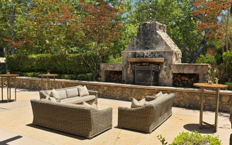 a patio with a stone fireplace and furniture