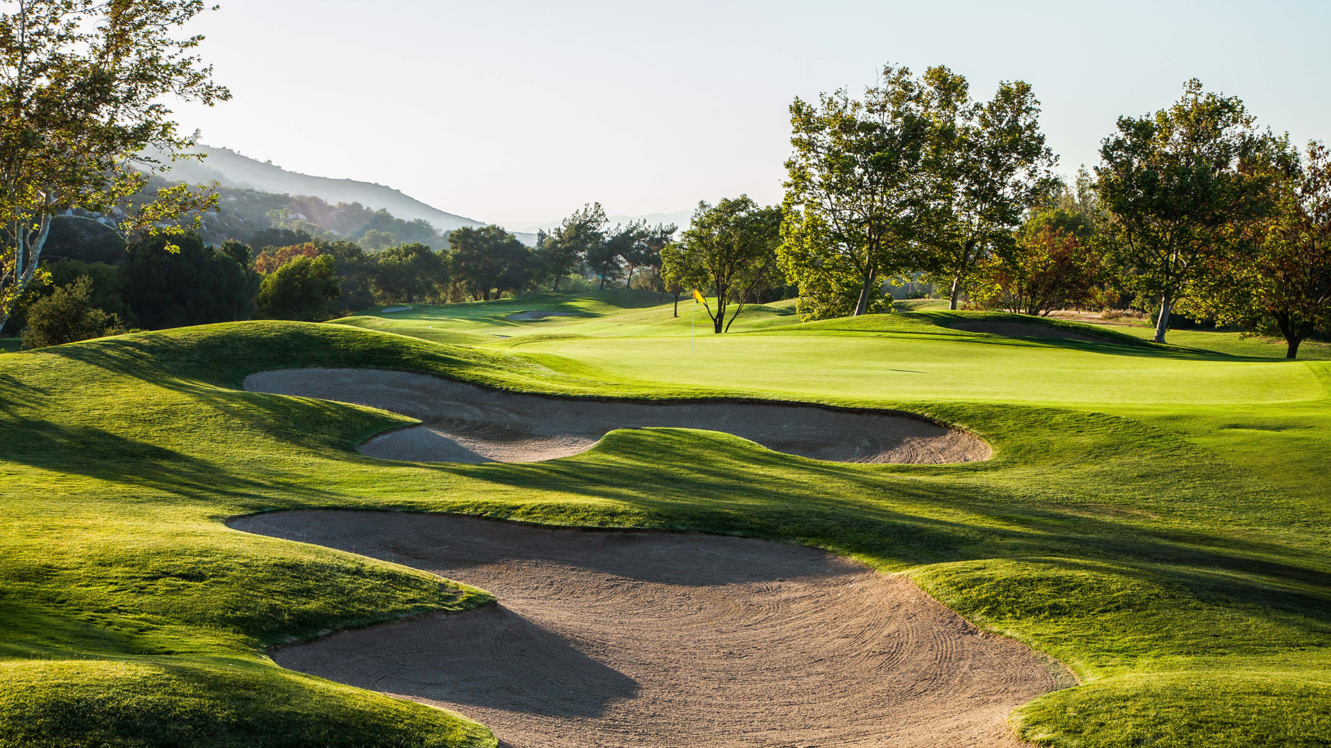 a golf course with sand bunkers and trees