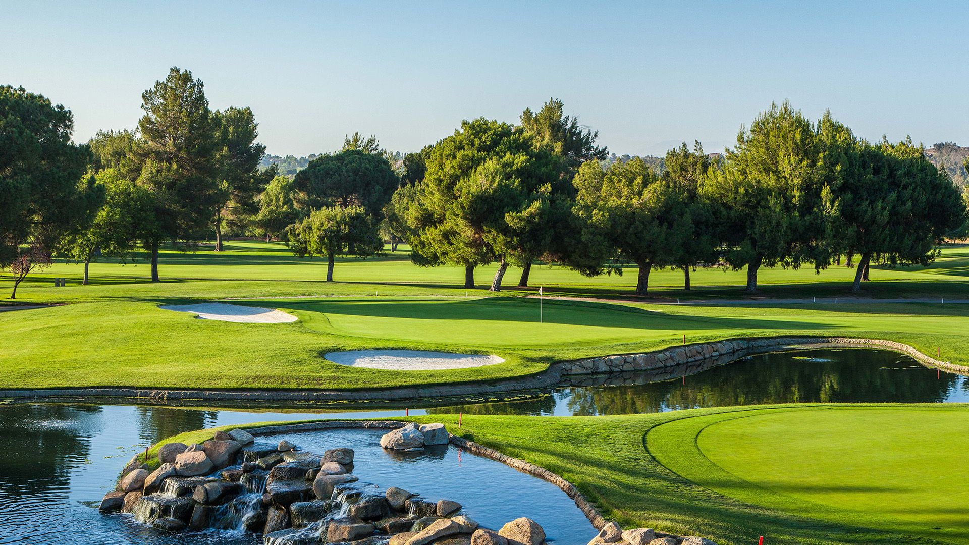a golf course with a river and trees