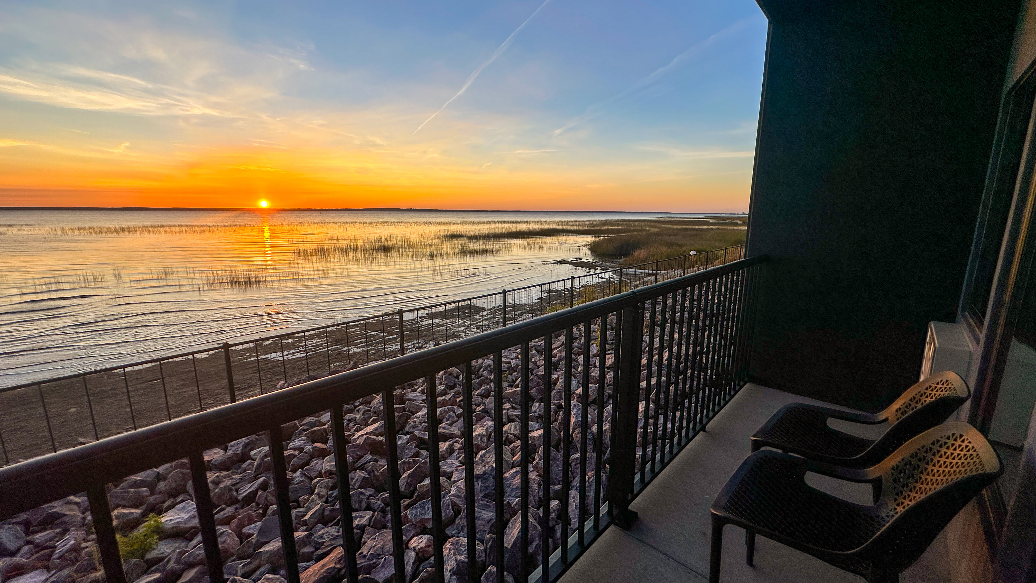 a balcony with a view of the sunset over the water