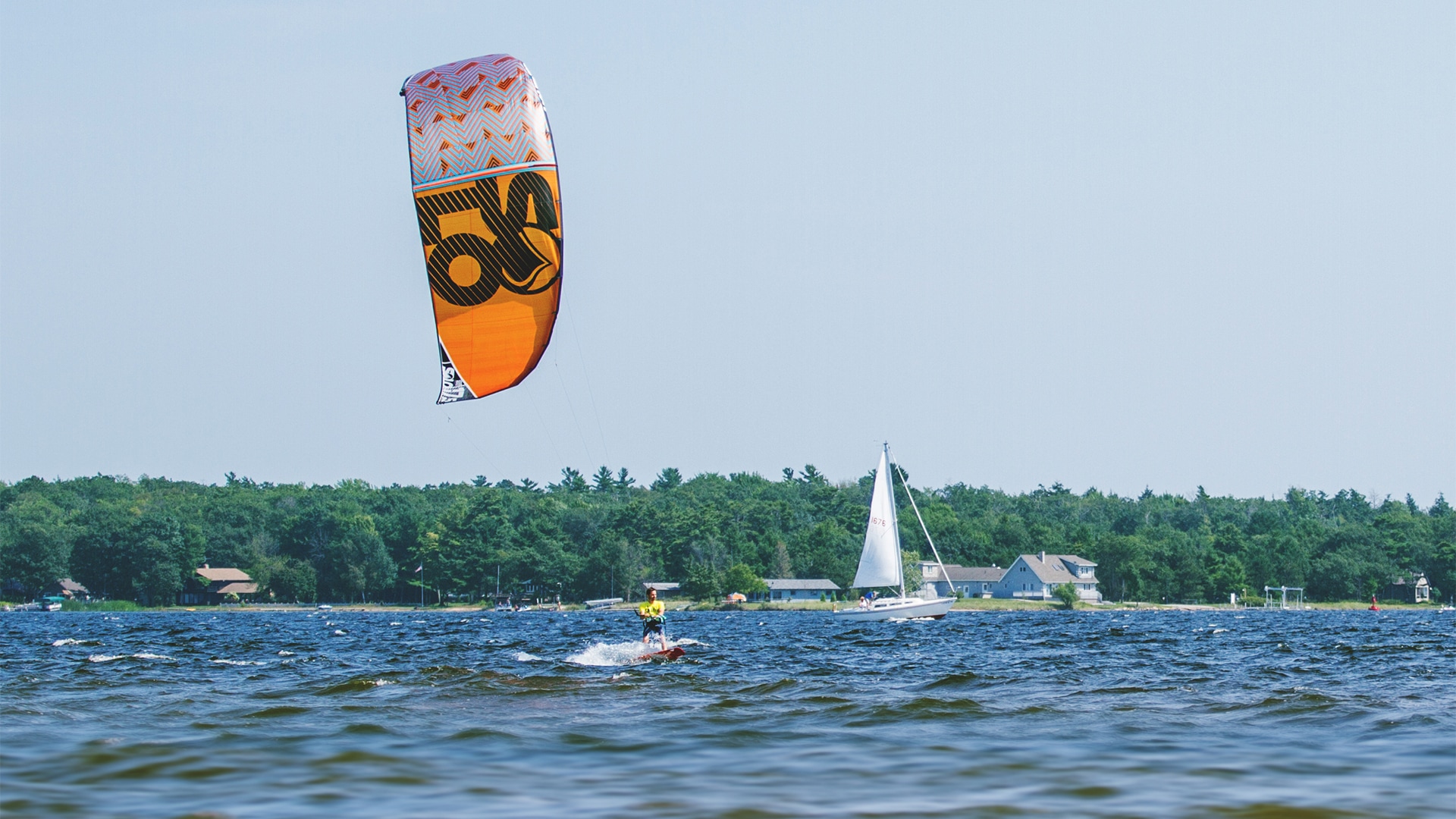 a person on a surfboard with a sailboat in the background
