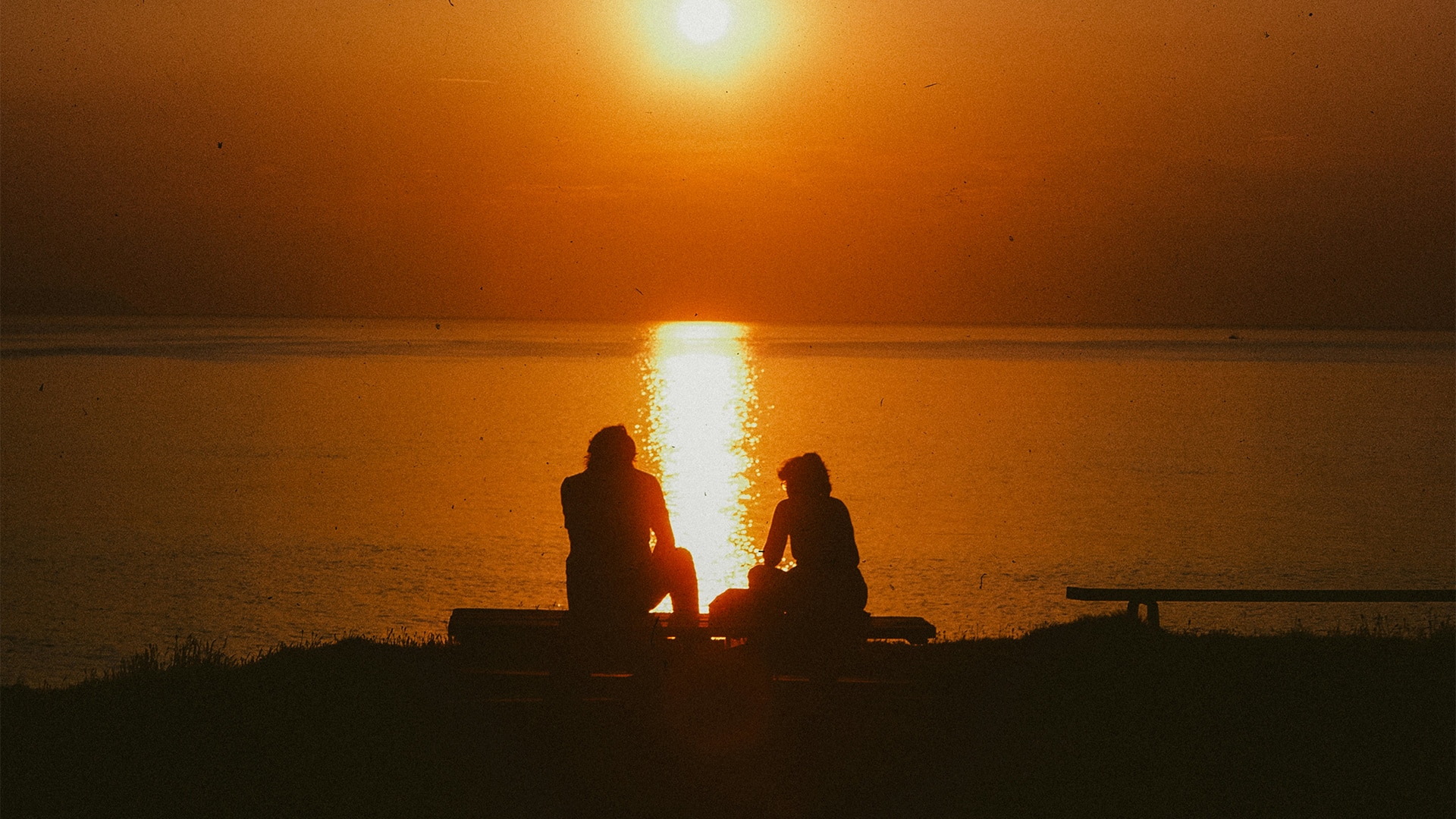 a group of people sitting on a bench by the water